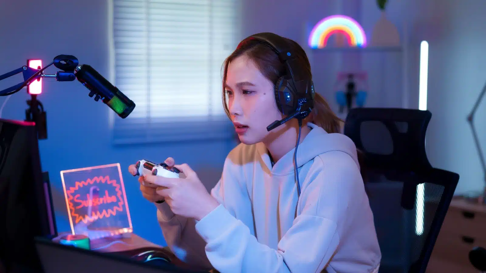 A woman livestreams while playing a game with a controller to represent the best Capture Card for Switch Streamers.