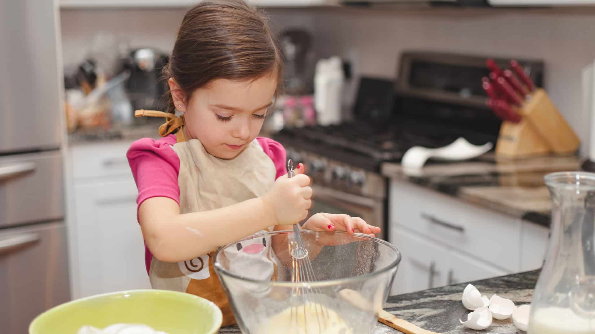 Young girl mixing batter in the kitchen by herself.