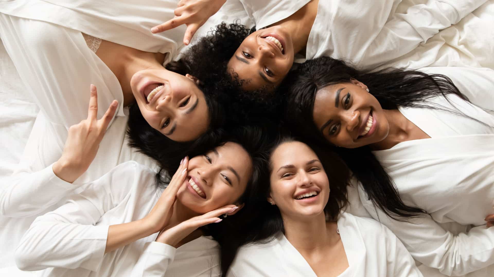 Top view of a group of women laying in a circle all are wearing bathrobes.