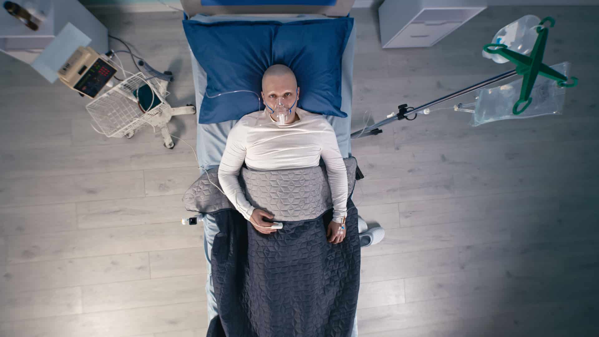 A person in a sterile hospital bed on life support surrounded by machines.