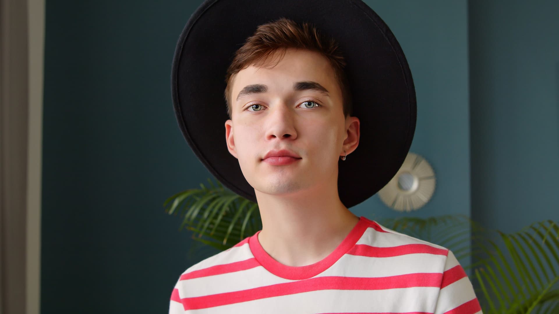 Teenage boy wearing a unique hat and a striped shirt.