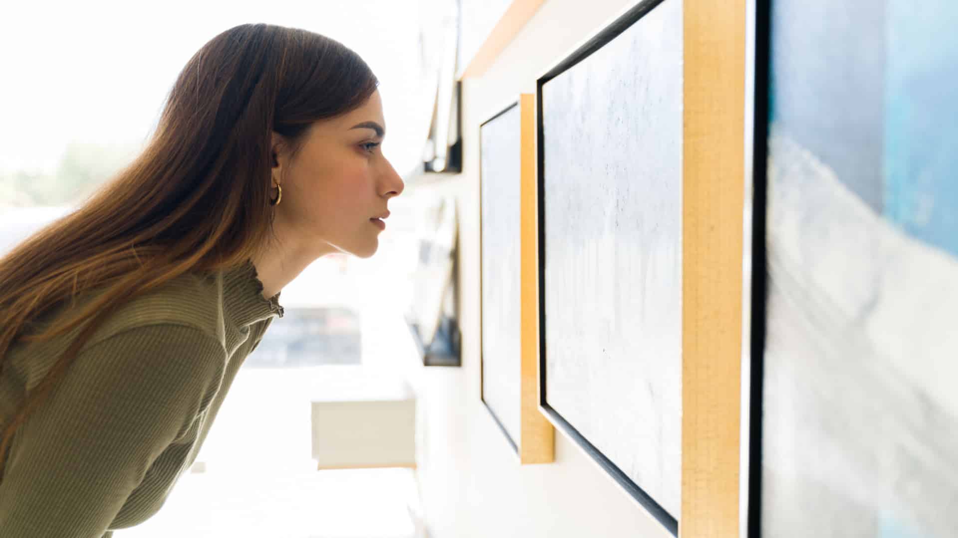 Woman looking at artworks on the wall in an art gallery.