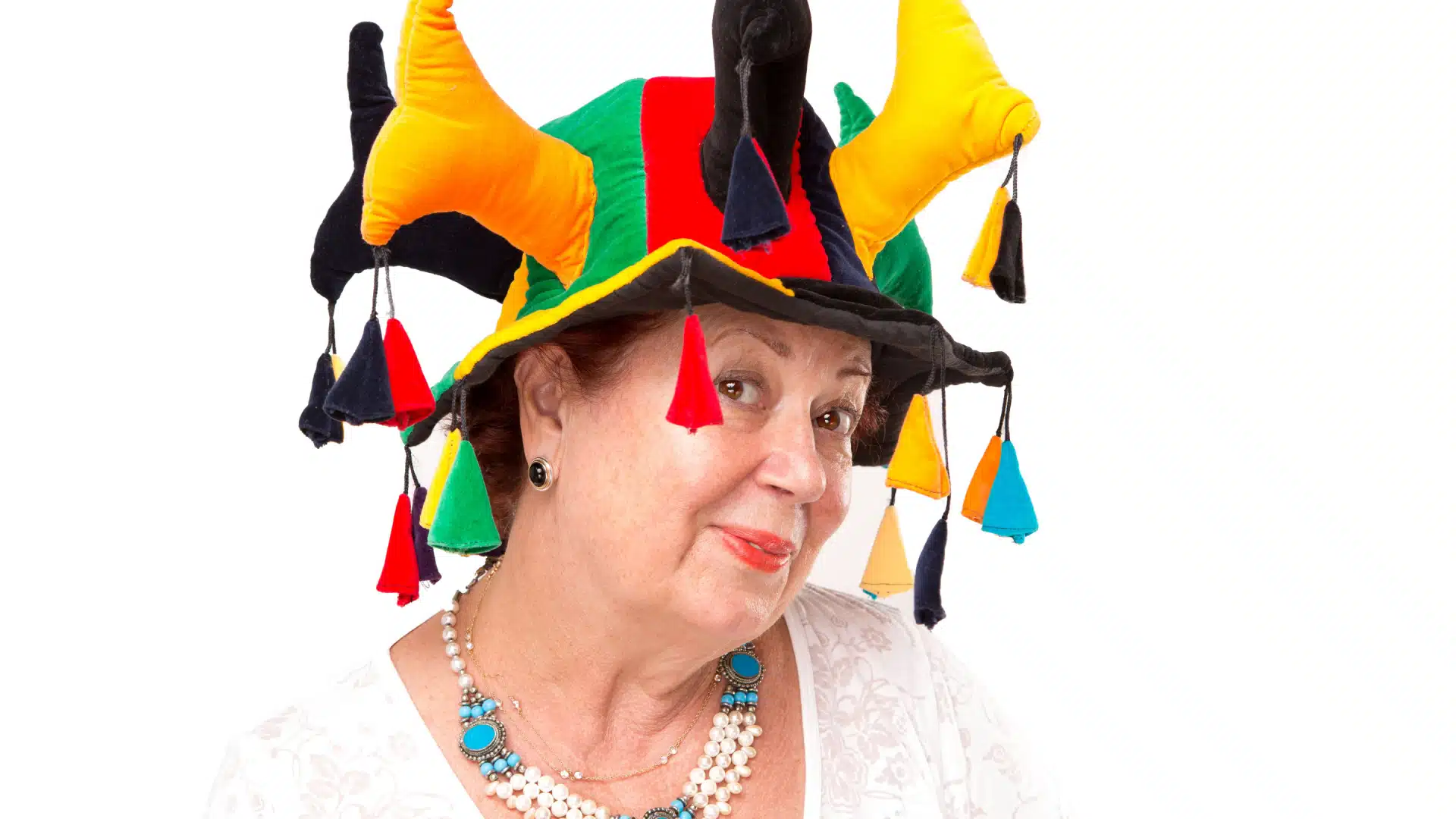 Smiling older woman wearing nice clothes and a colorful jester's hat. 