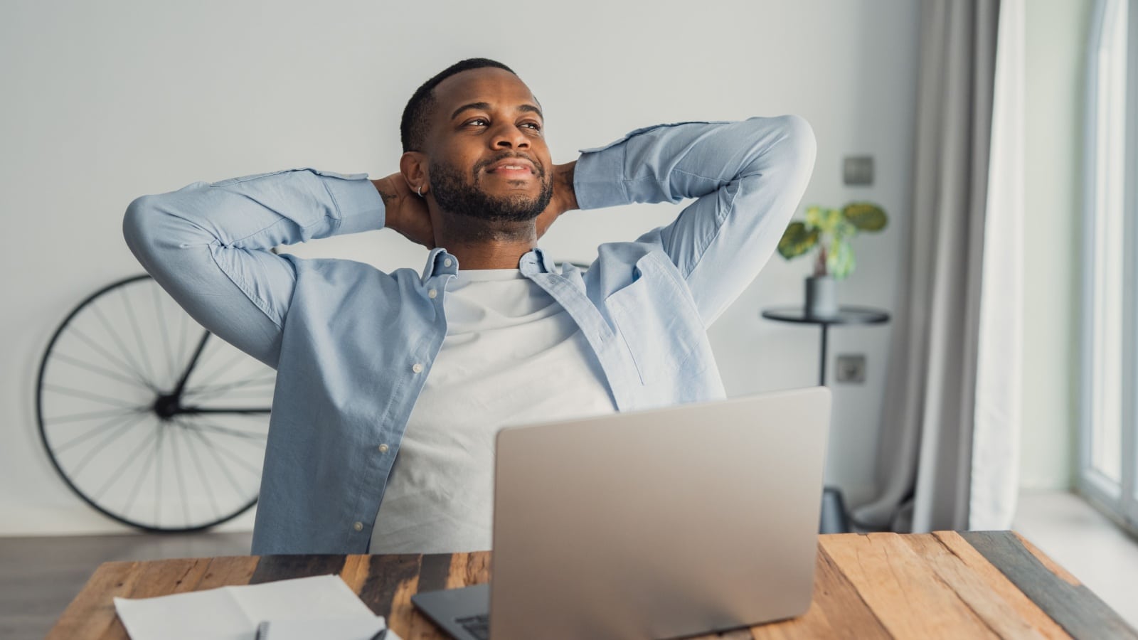 A writer leans back from his laptop, satisfied, as he finishes the final chapter.