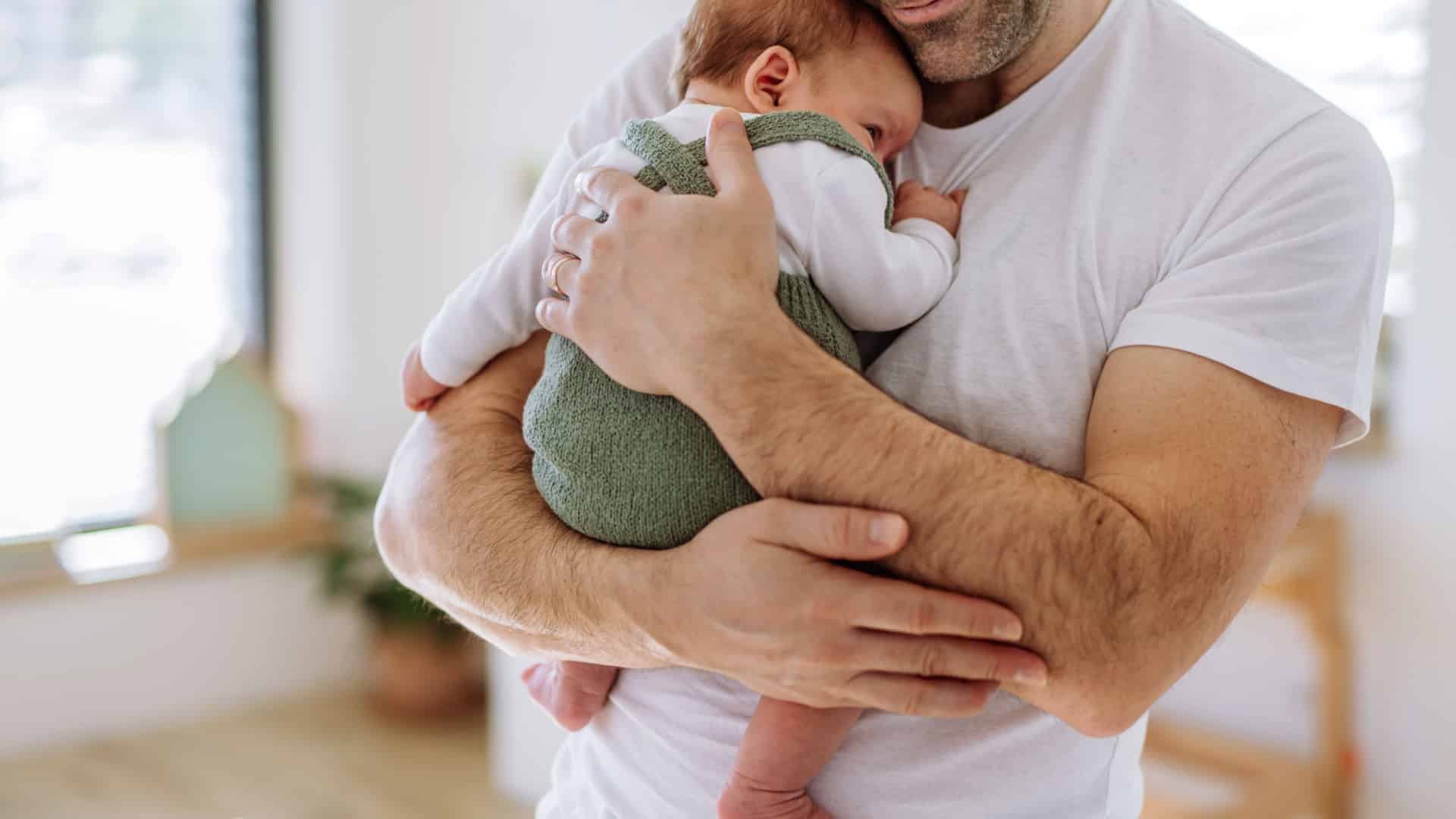 Close up of a father holding his baby close to his chest.