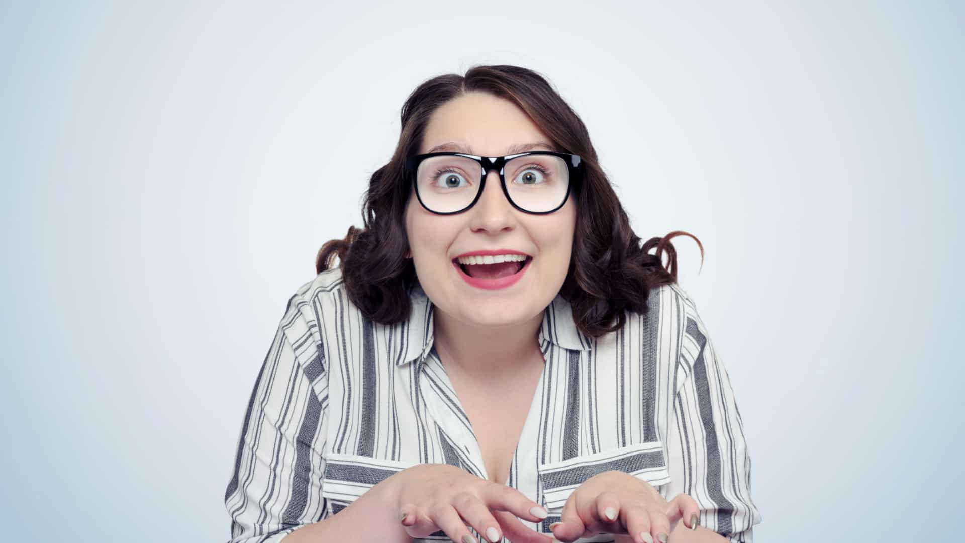Happy obsessed woman typing on a keyboard looking happily into what would be a computer screen.