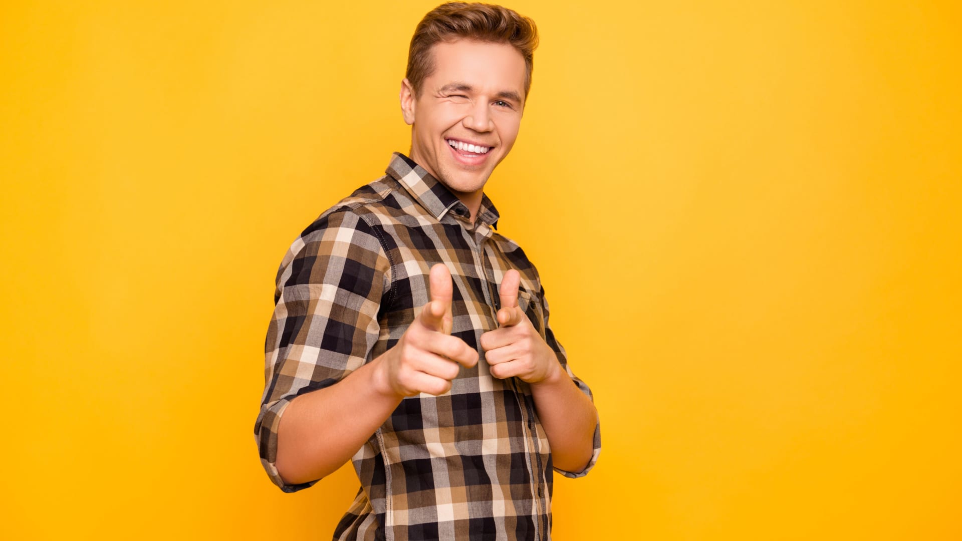 Smiling man facing sideways but winking and pointing towards the camera.