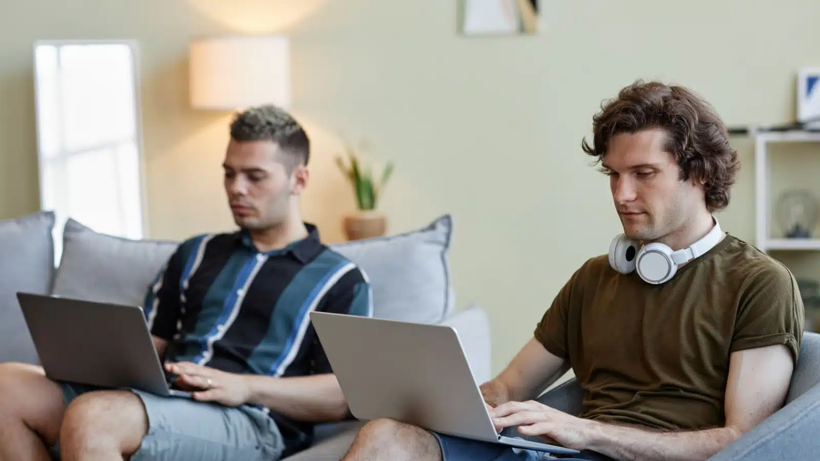 Roommates hanging out in the living room. Both are on their laptops.