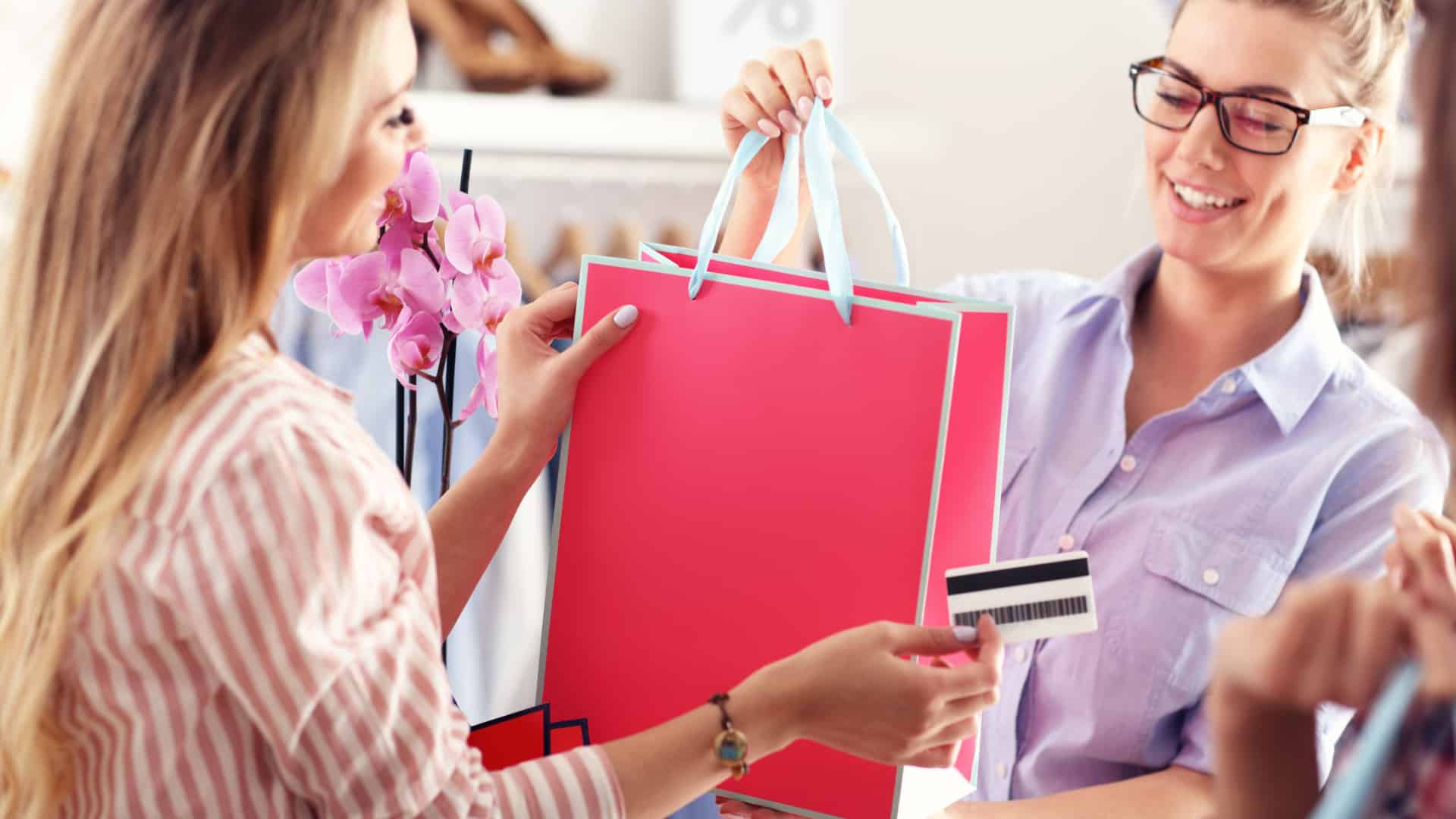 Woman buying something in a pink bag from a store clerk.