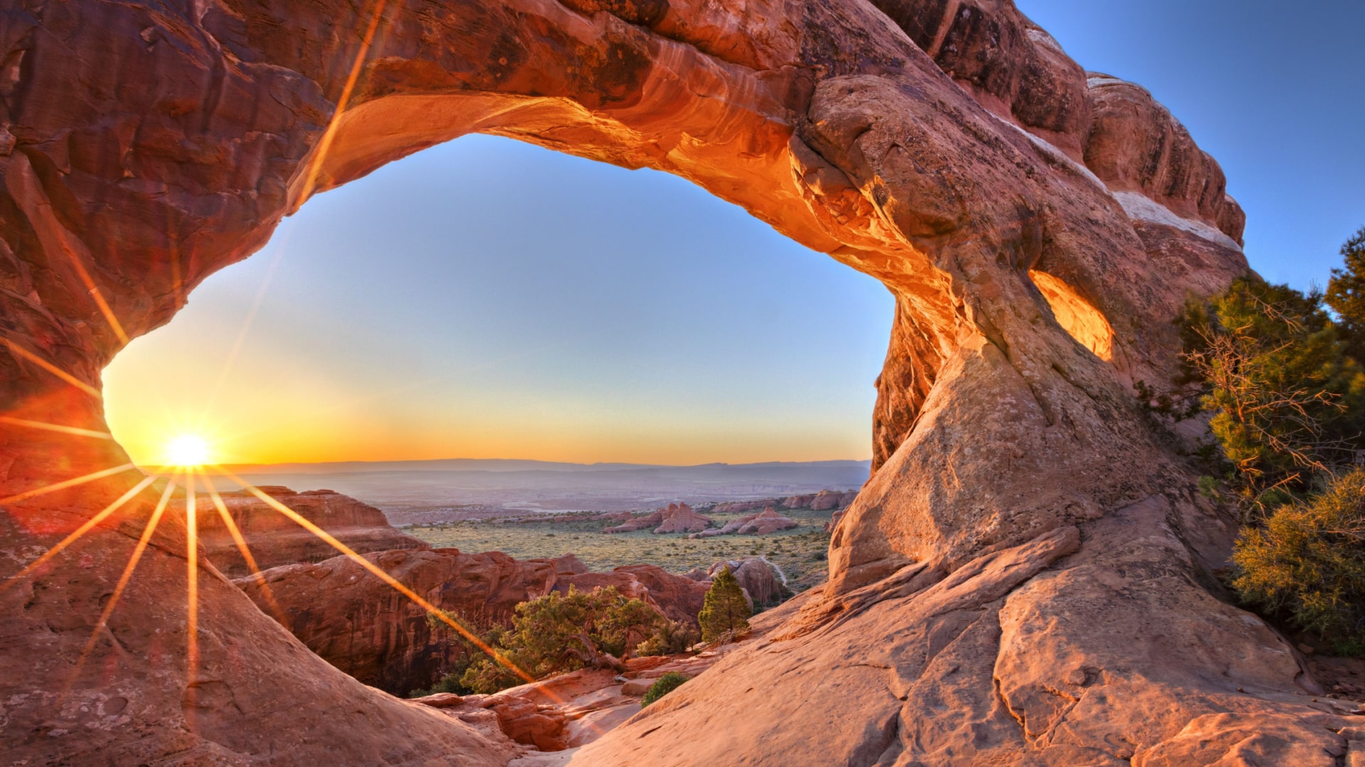 Sun shining through one of the arches at sunrise, Arches National Park in Utah.