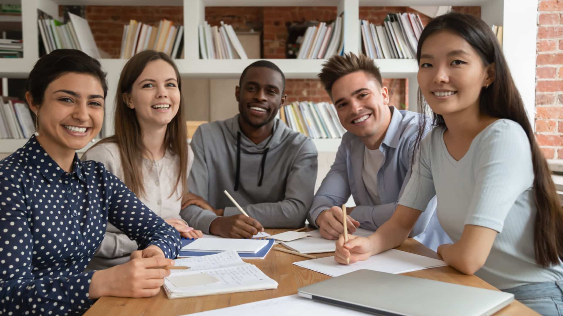 A diverse group of college students sitting around a table at a library.