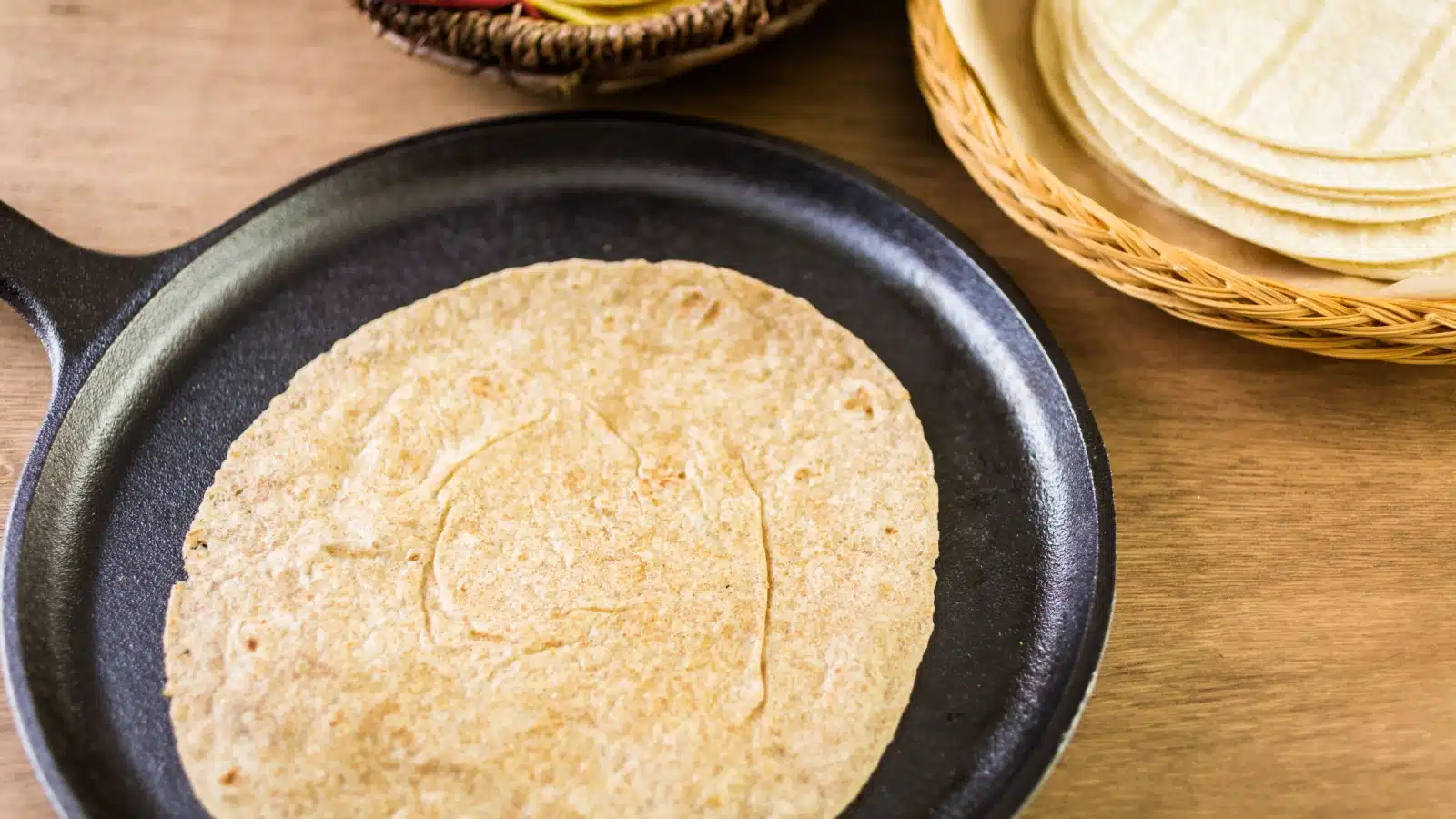 A corn tortilla cooking in a frying pan.
