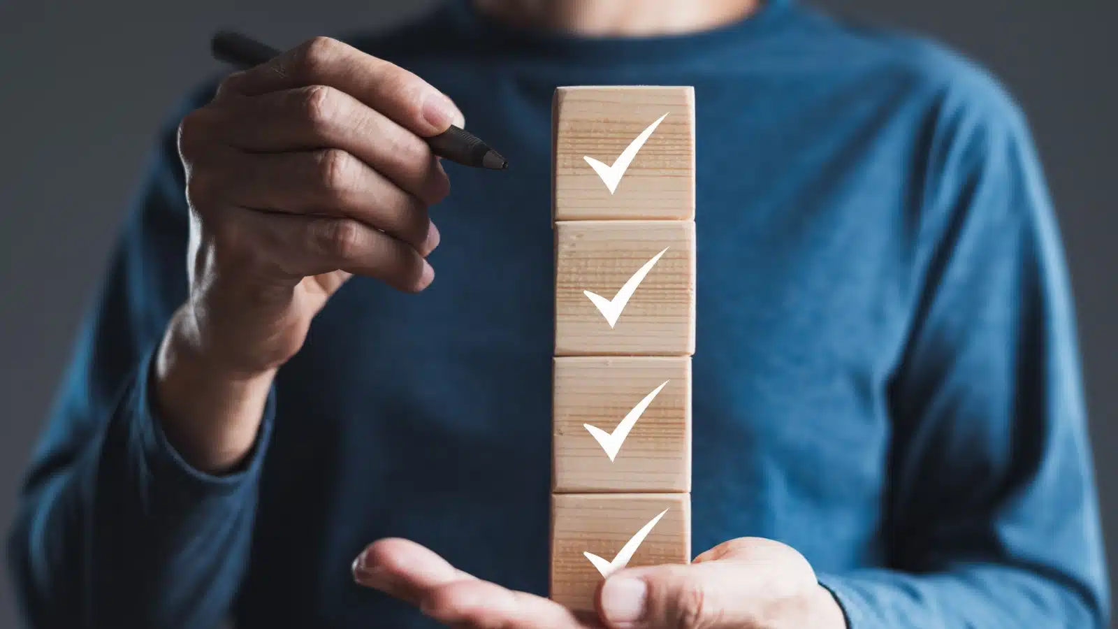 A woman holds a vertical stack of wooden blocks with check marks on them to represent defining priorities.