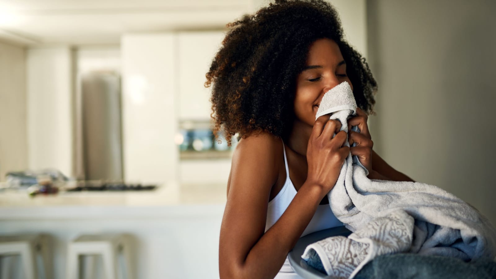 A happy woman sniffs laundry fresh from the dryer.