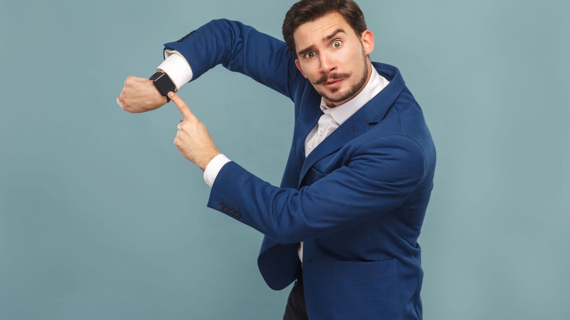 A boss with a stupid look on his face dramatically points at his watch.