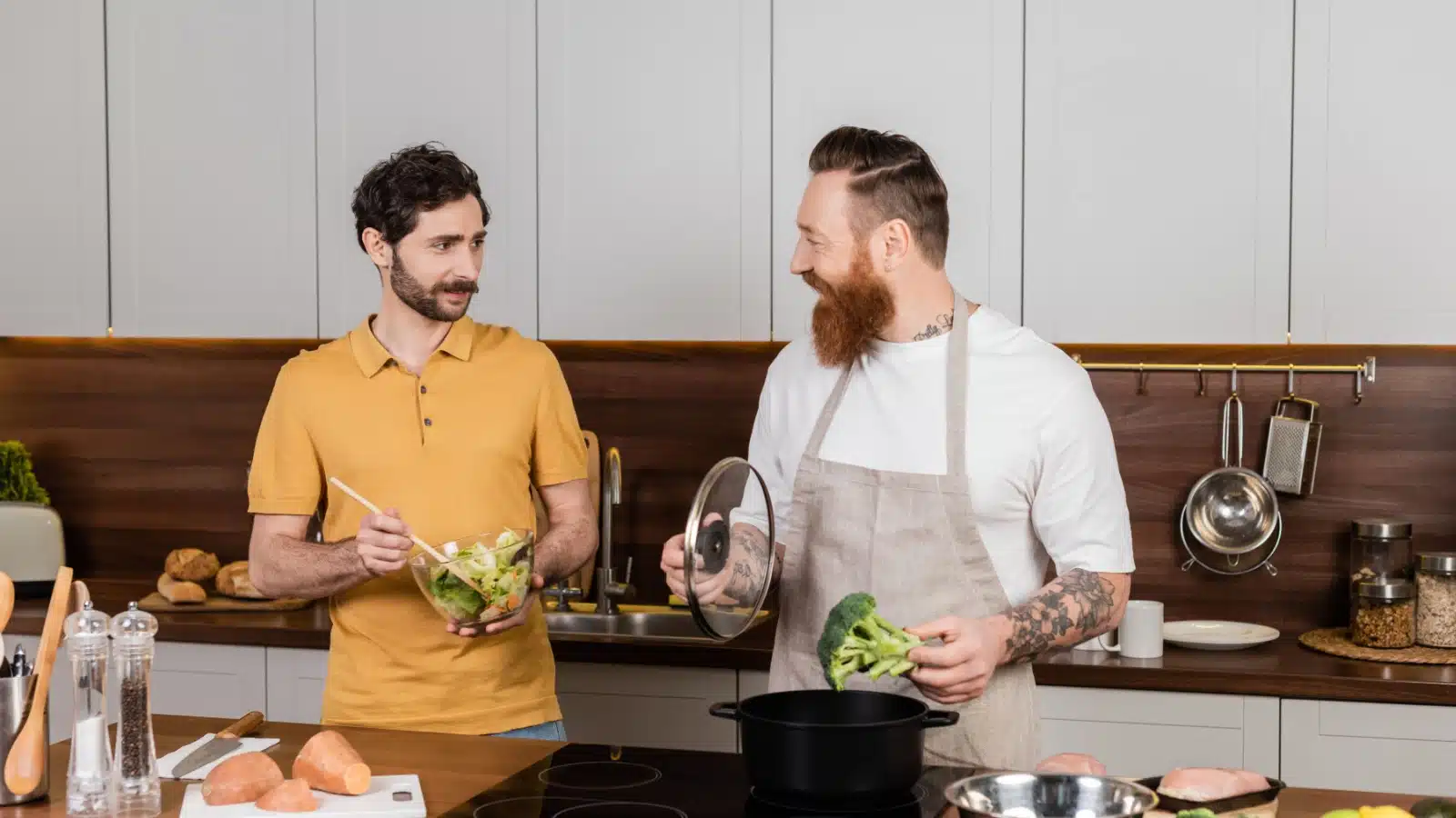 A man is cooking broccoli by dropping it in a pot. 