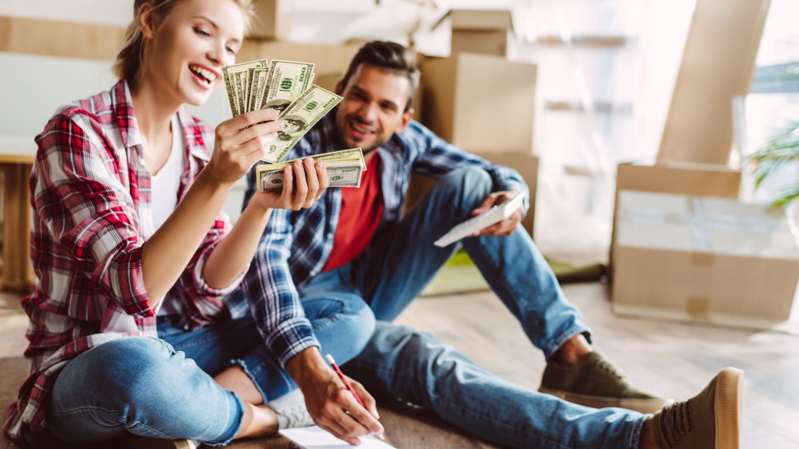 A happy couple sits in their new home and counts money.