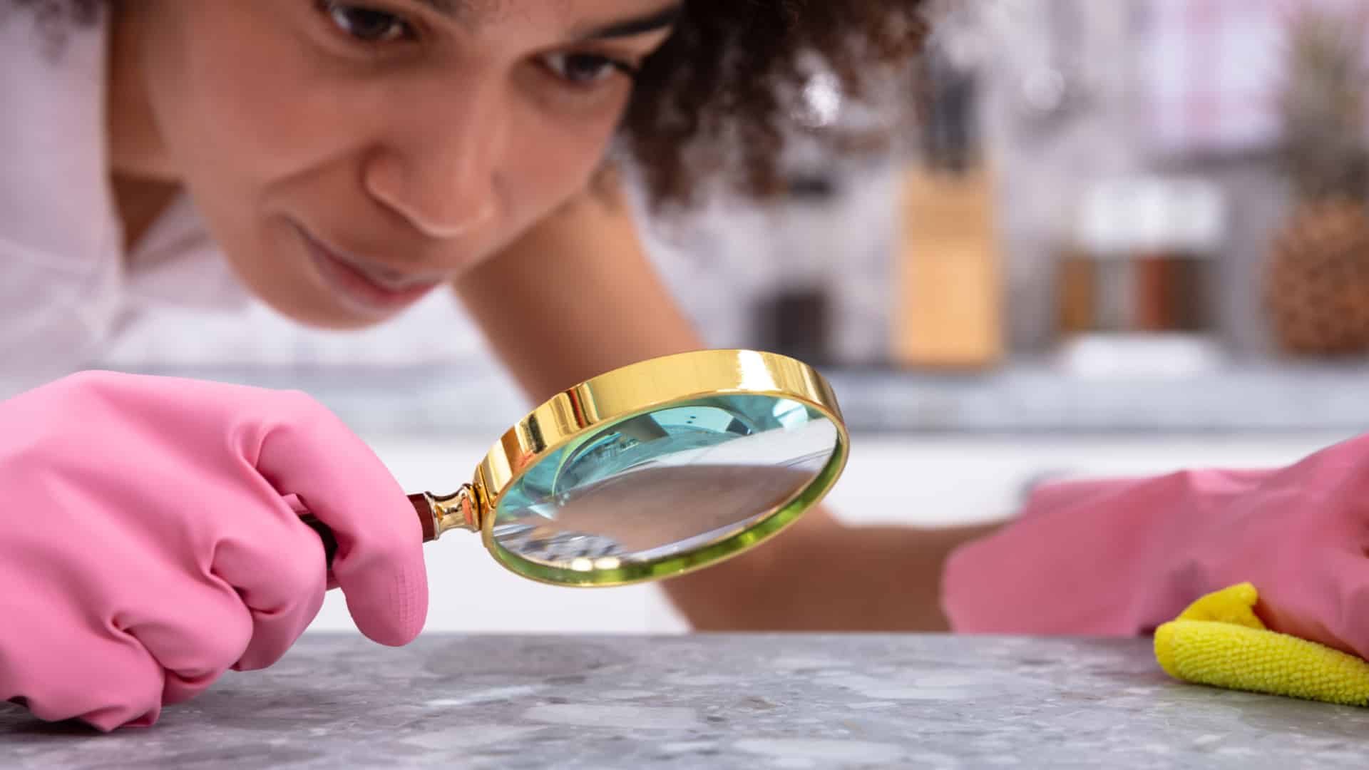 Perfectionist woman examing counters with a magnifying glass.