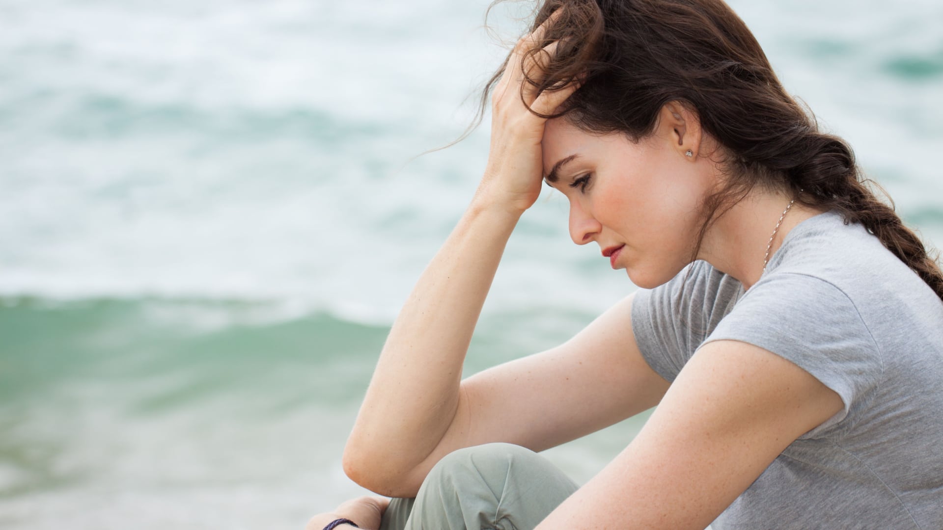 Sad depressed woman sitting on the beach.