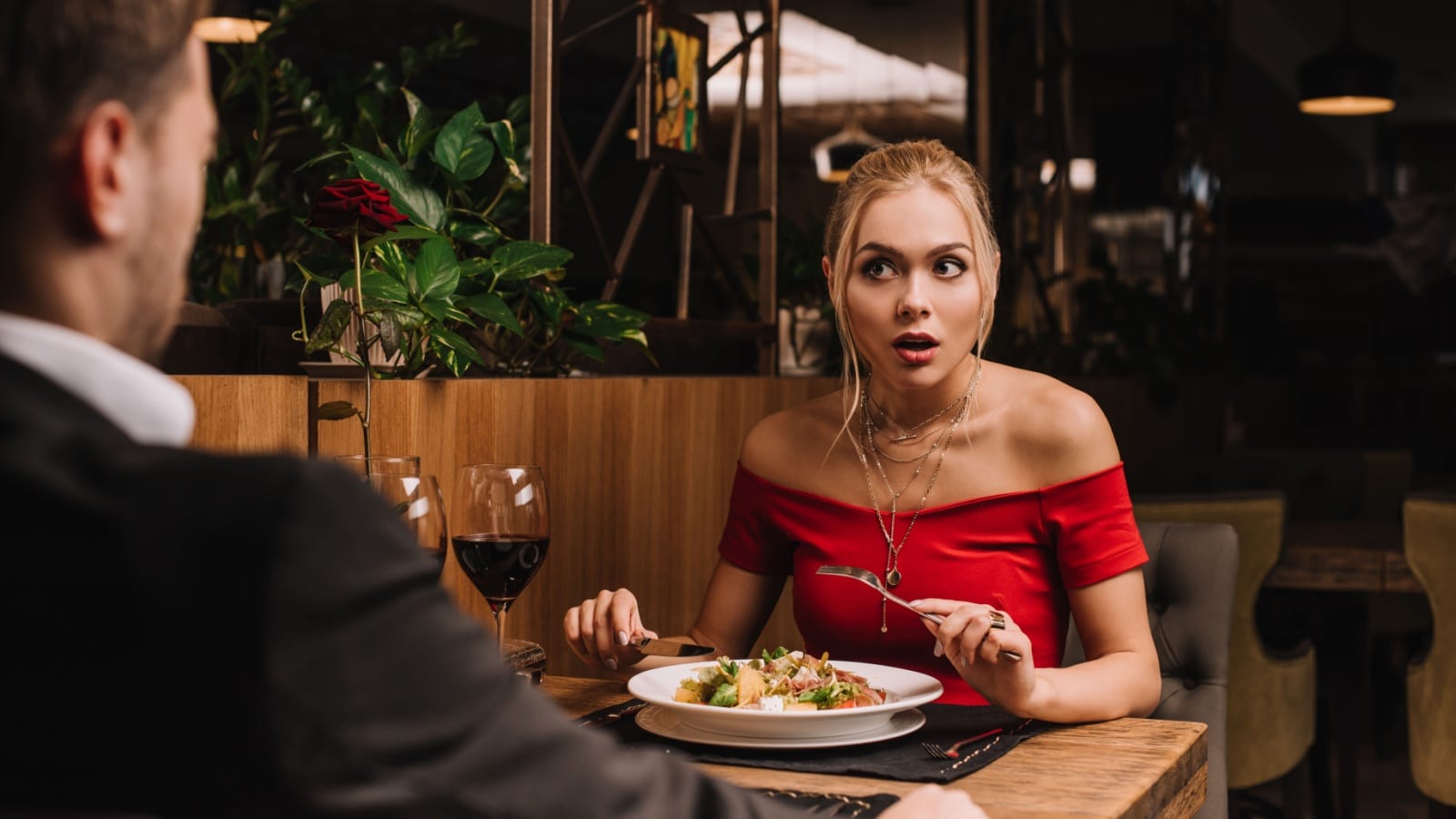 A woman looks at her date with a shocked expression as if he just revealed something horrifying on a date.