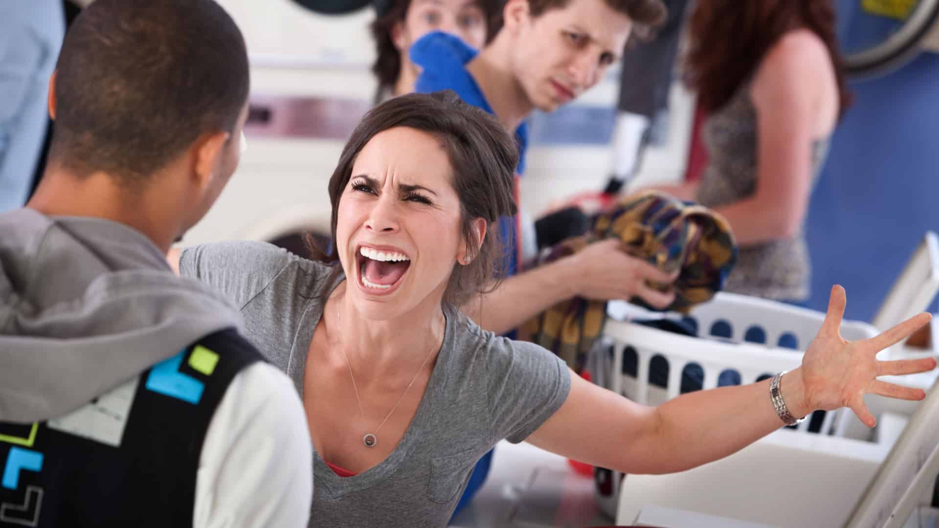 A frustrated woman yells at a man in a laundrymatt.