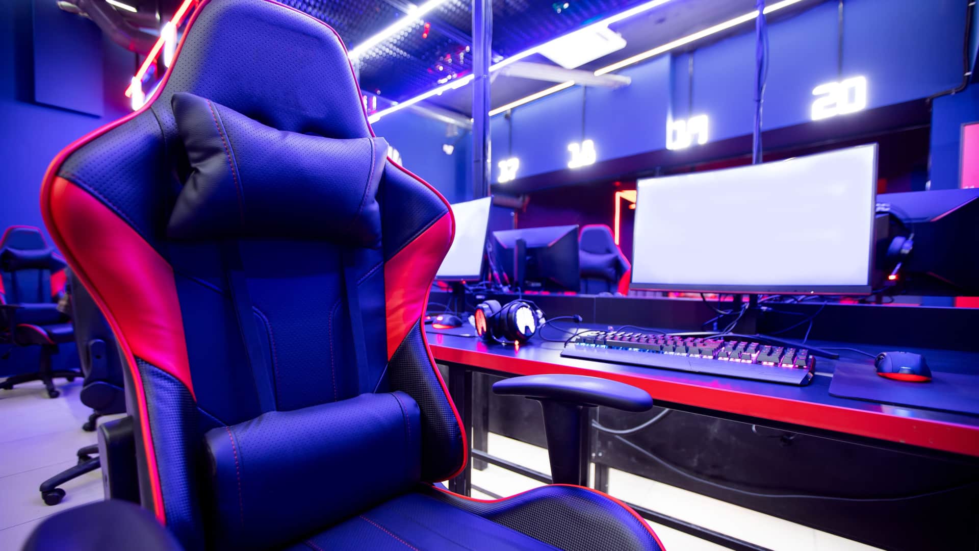 Comfortable looking professional gaming chair in front of computer set up with blue/purple filter.