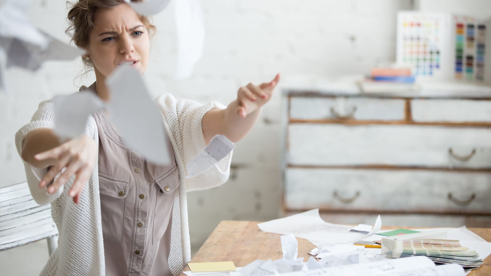 Frustrated woman throwing papers in the air as if to quit her job to represent nobody wants to work anymore.