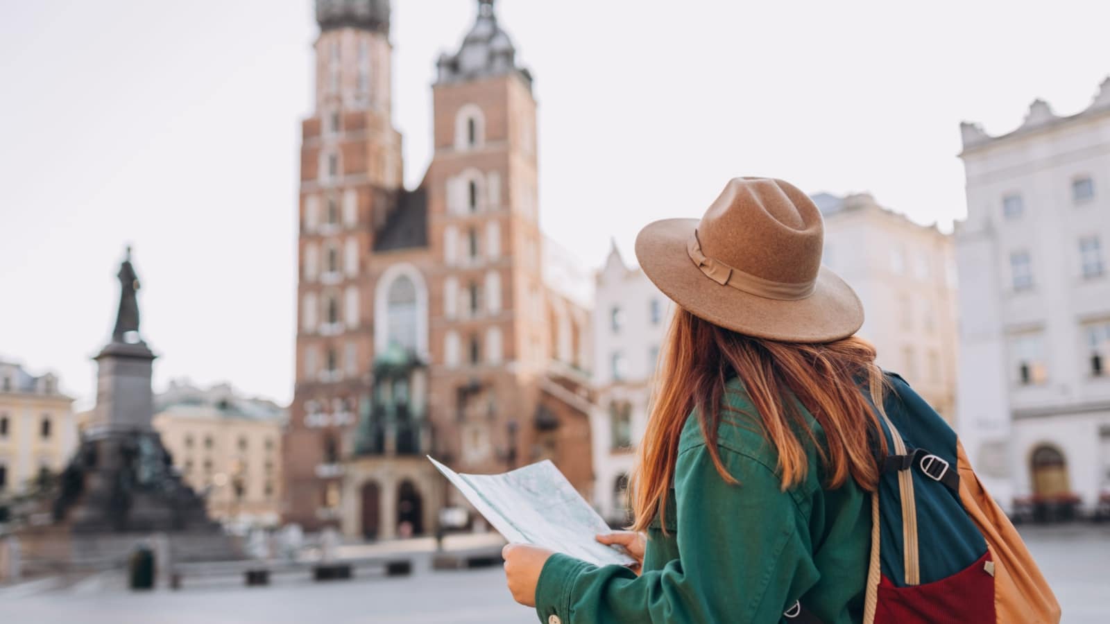 A tourist holding a map while exploring the square of a pretty city.