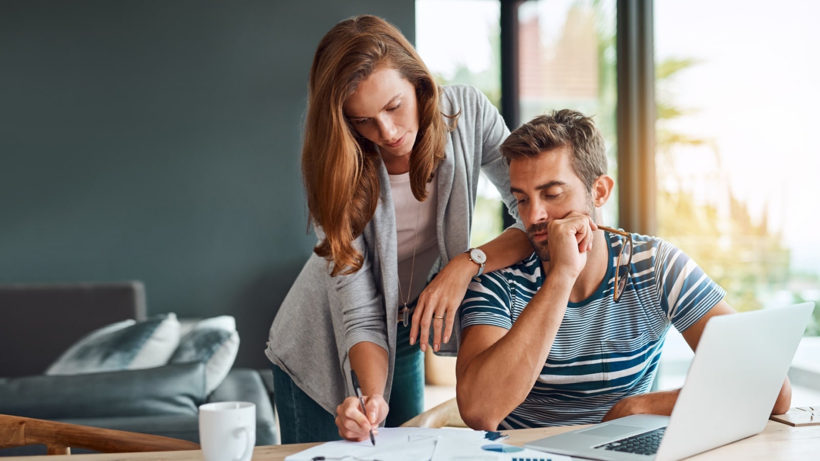 A stressed looking couple reviewing their financial statements and doing taxes to represent legal scams.