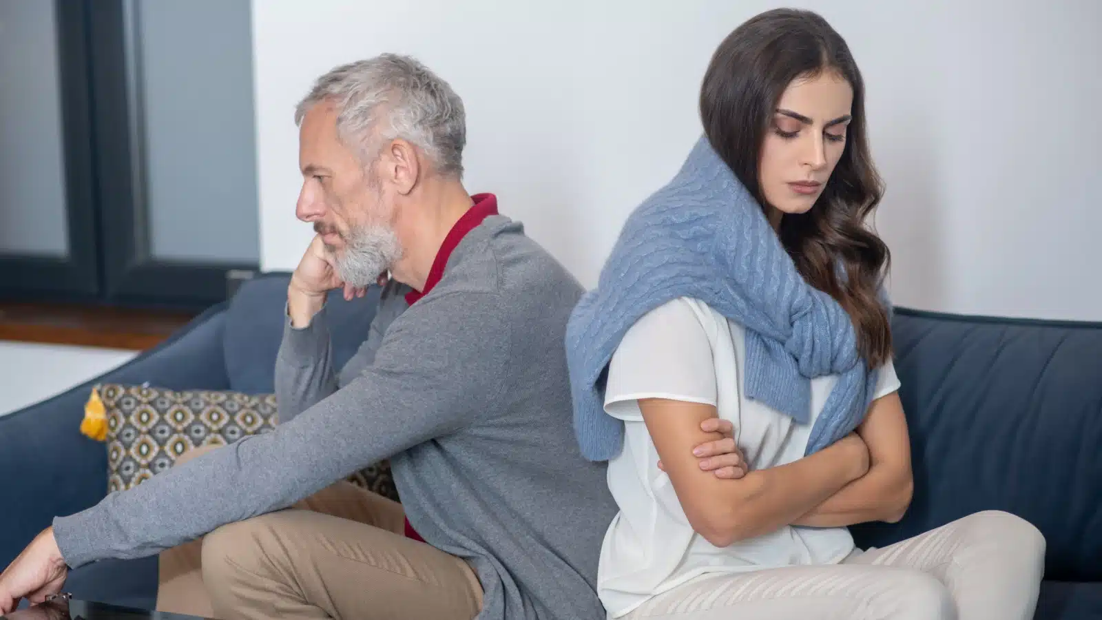 A couple in an age gap relationship sit back to back, in a fight.