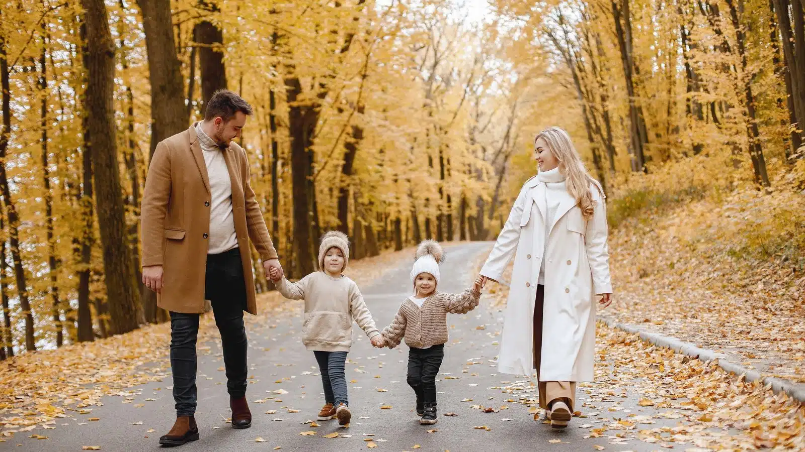Parents and their two young children walking on a road in the autumn to represent the best fall activities for families.