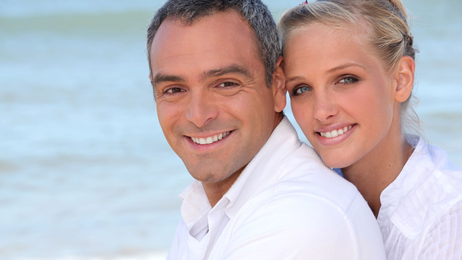A happy couple in an age gap relationship by the ocean.