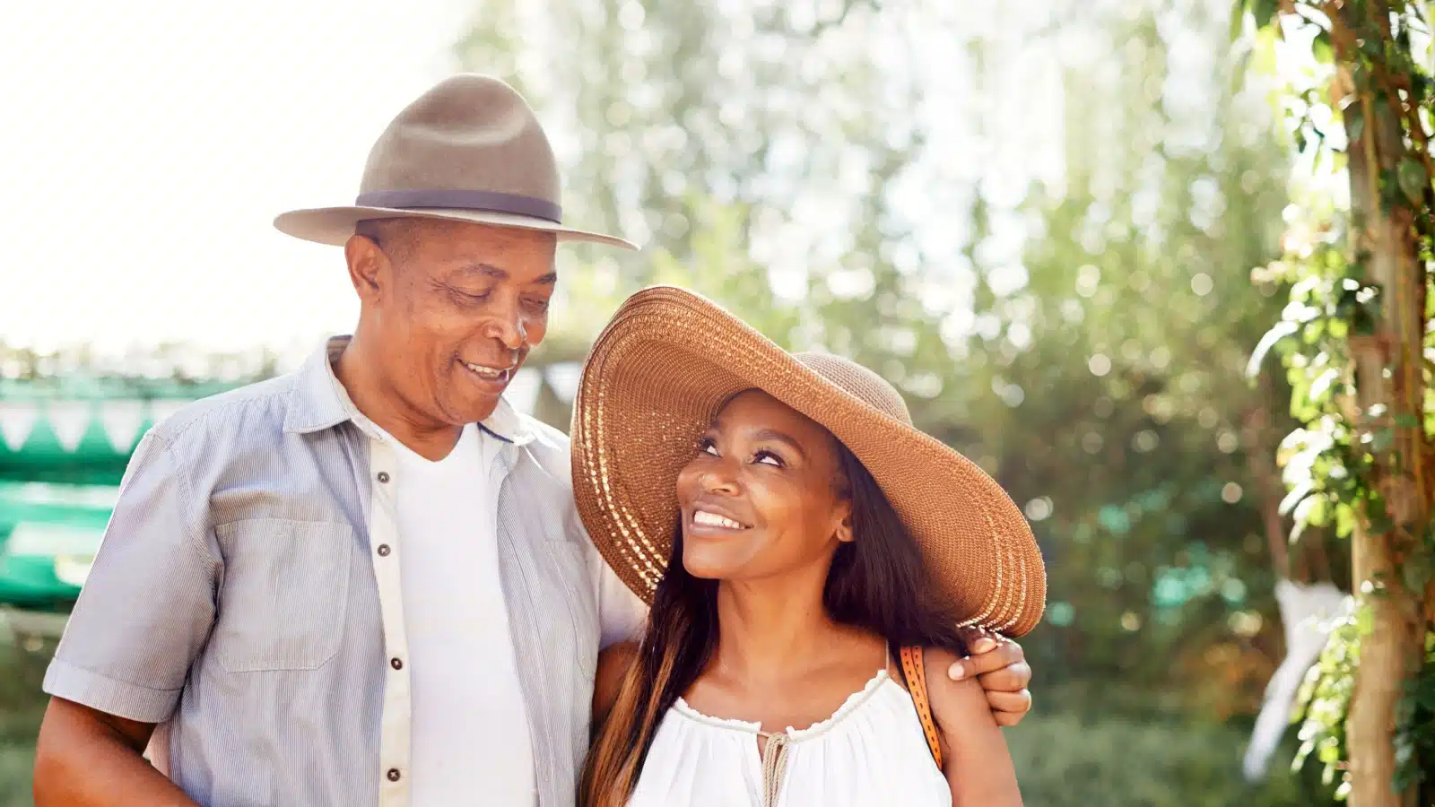 A happy couple in an age gap relationship walk outside in a garden.
