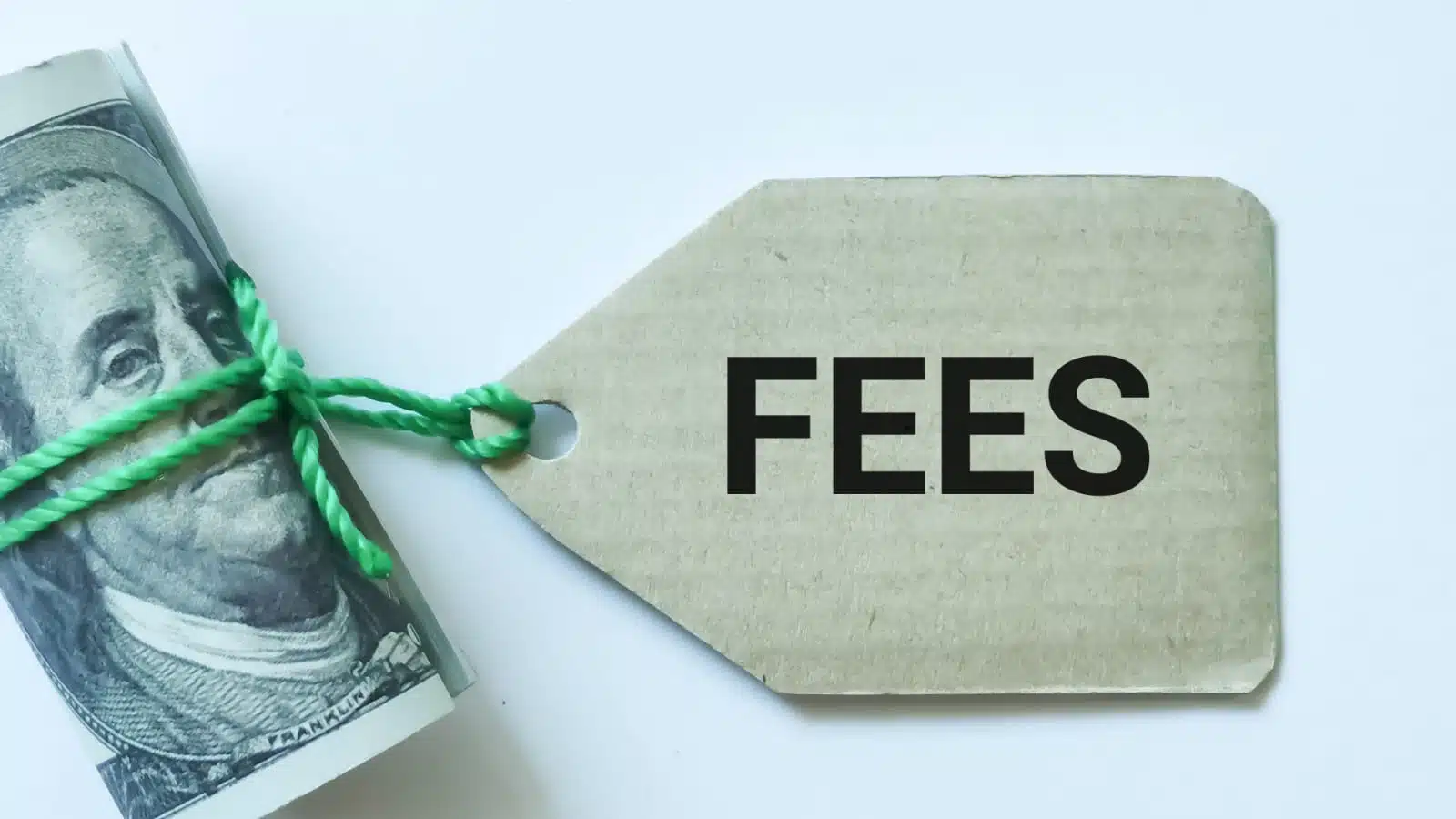 A hundred dollar bill rolled up and tagged with a cardboard tag labeled "fees."