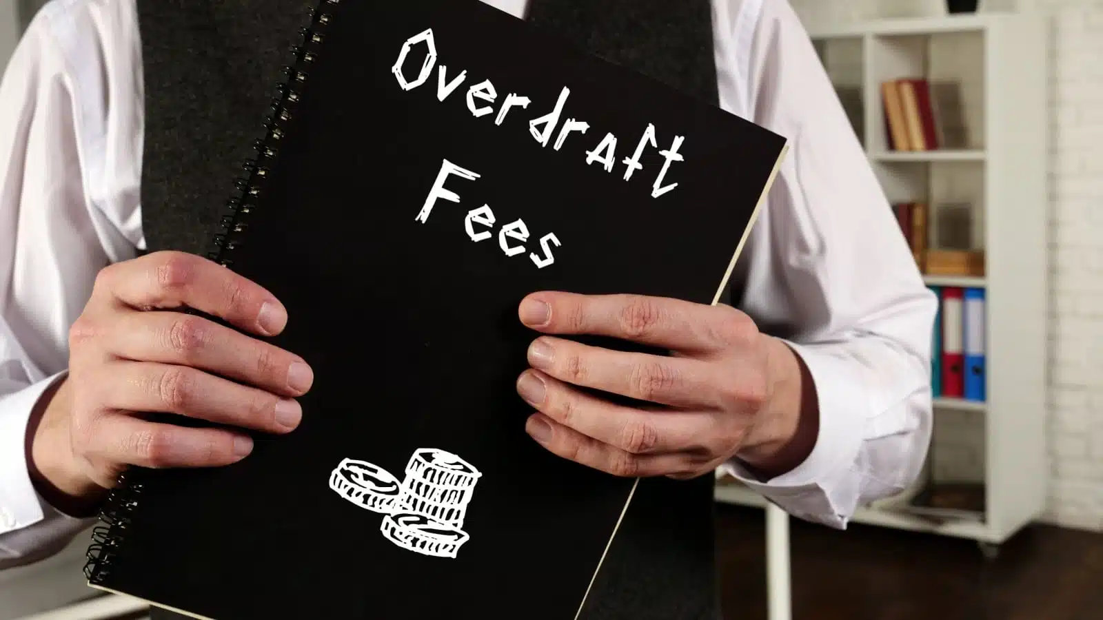 A banker holding a ledger labeled "overdraft fees."