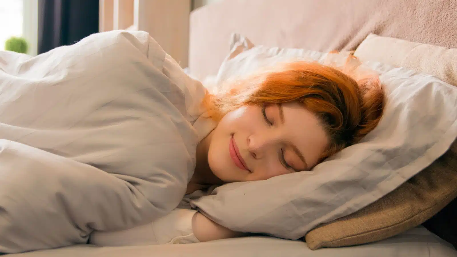 A content looking woman asleep in bed to represent getting a good night's sleep. 