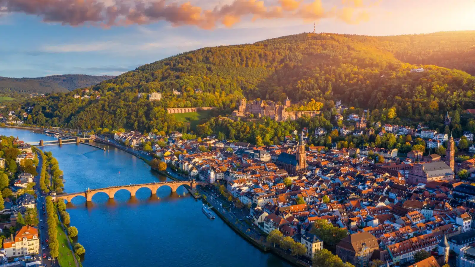 Aerial view of Heidelberg, Germany skyline, with the sun shining on the hill before it sets behind it.