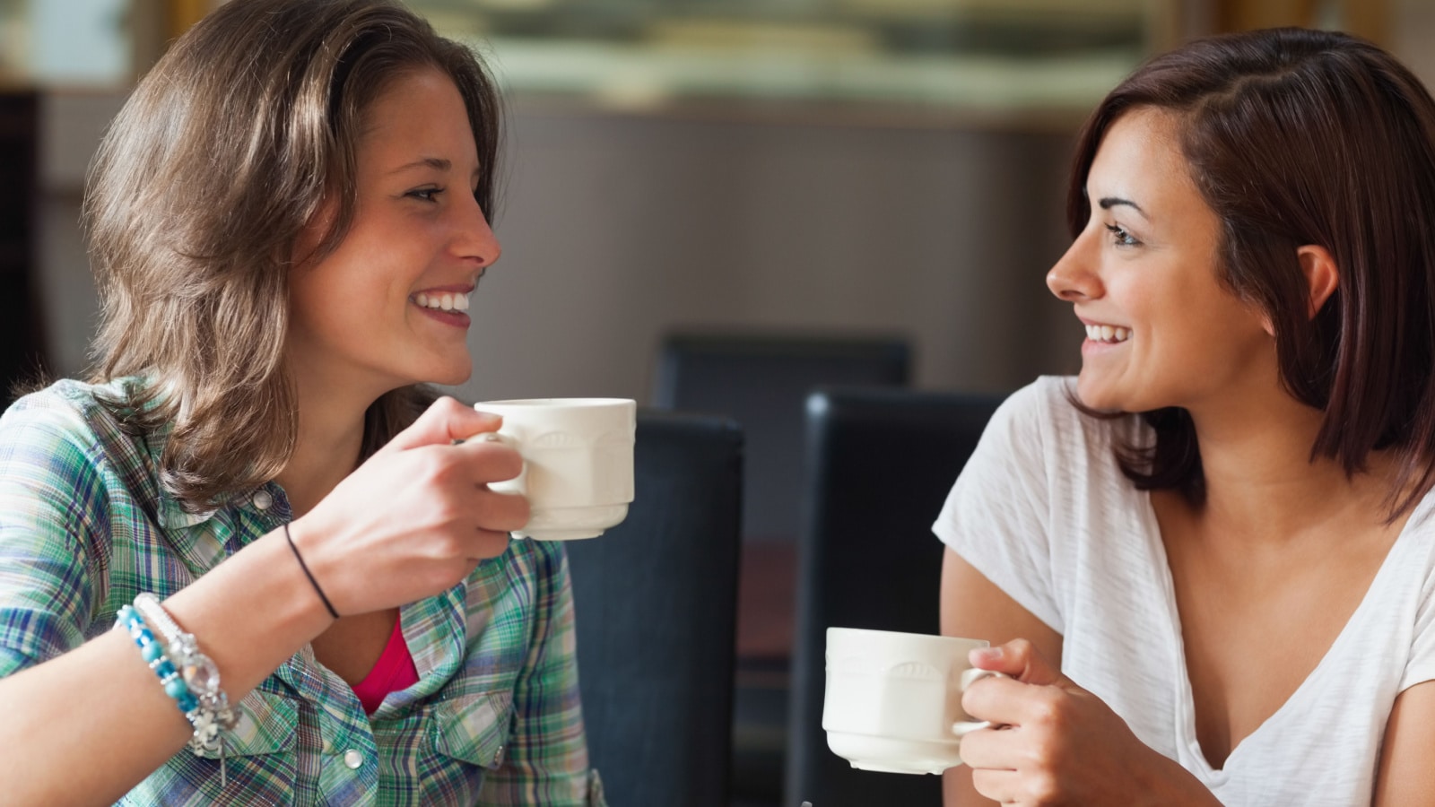 Two young women chatting over a cup of coffee.