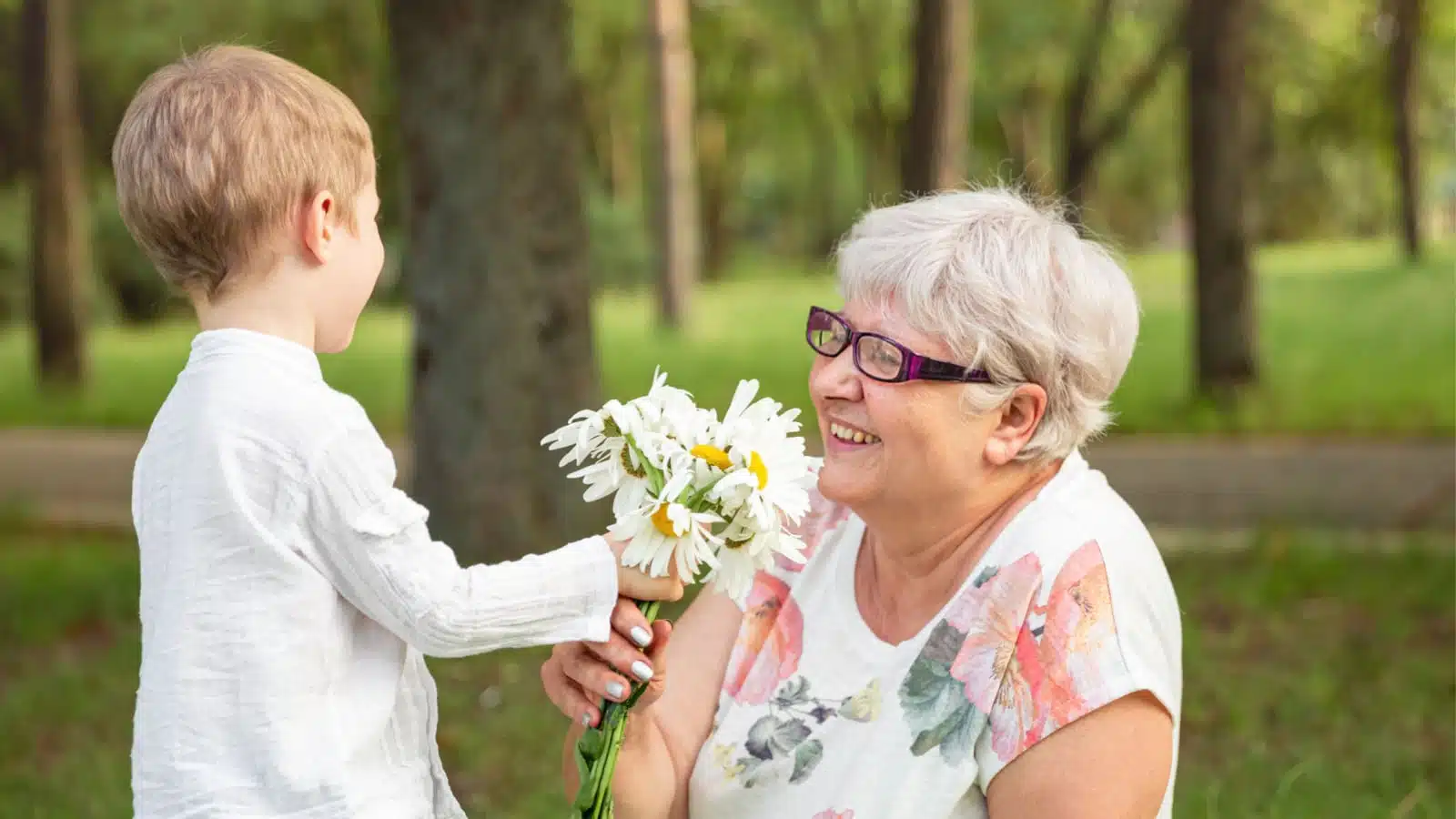 A little boy giving his grandmother a small bouquet of flowers.