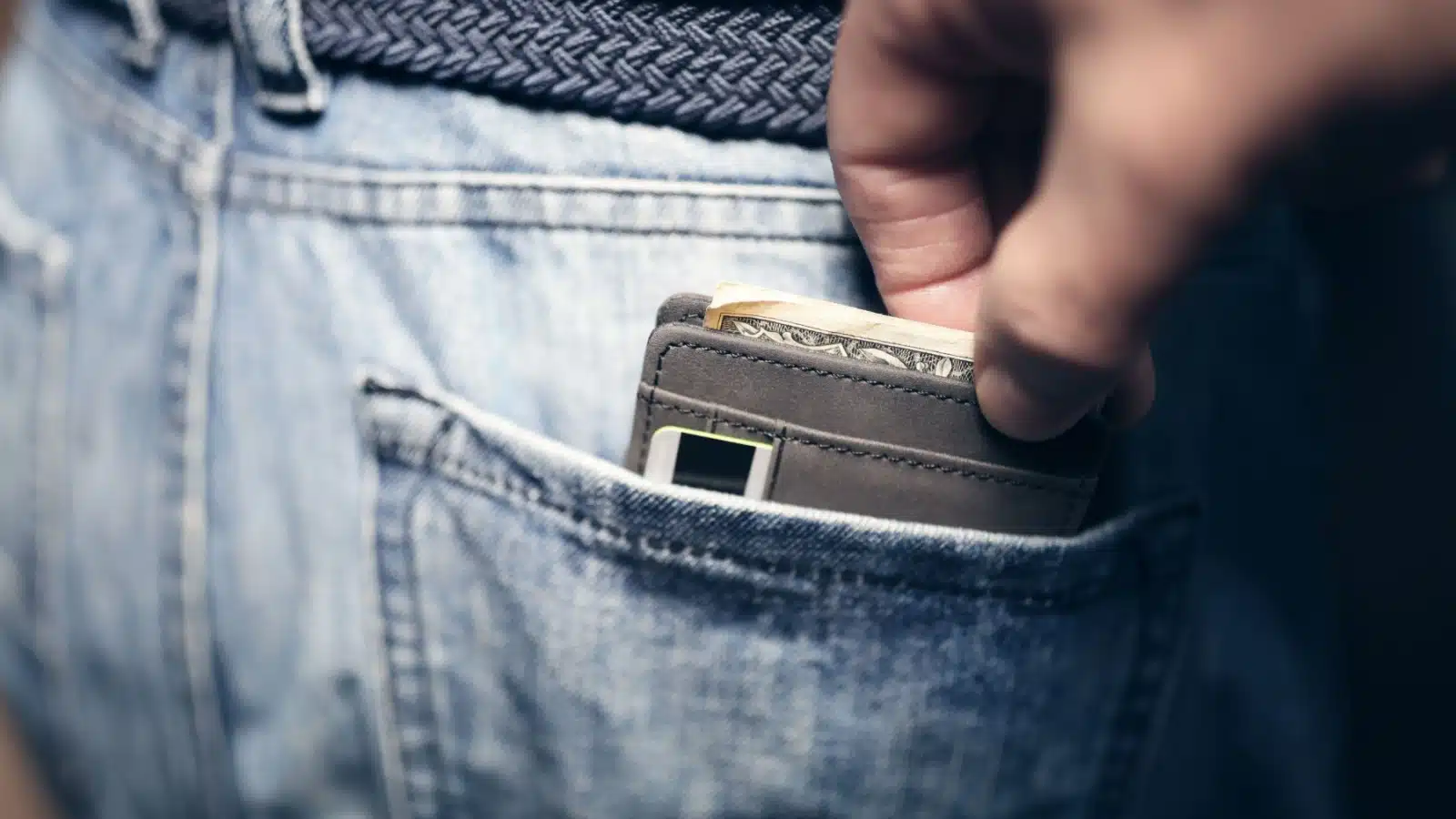 Close up of a pickpocket taking a wallet from a back pocket.