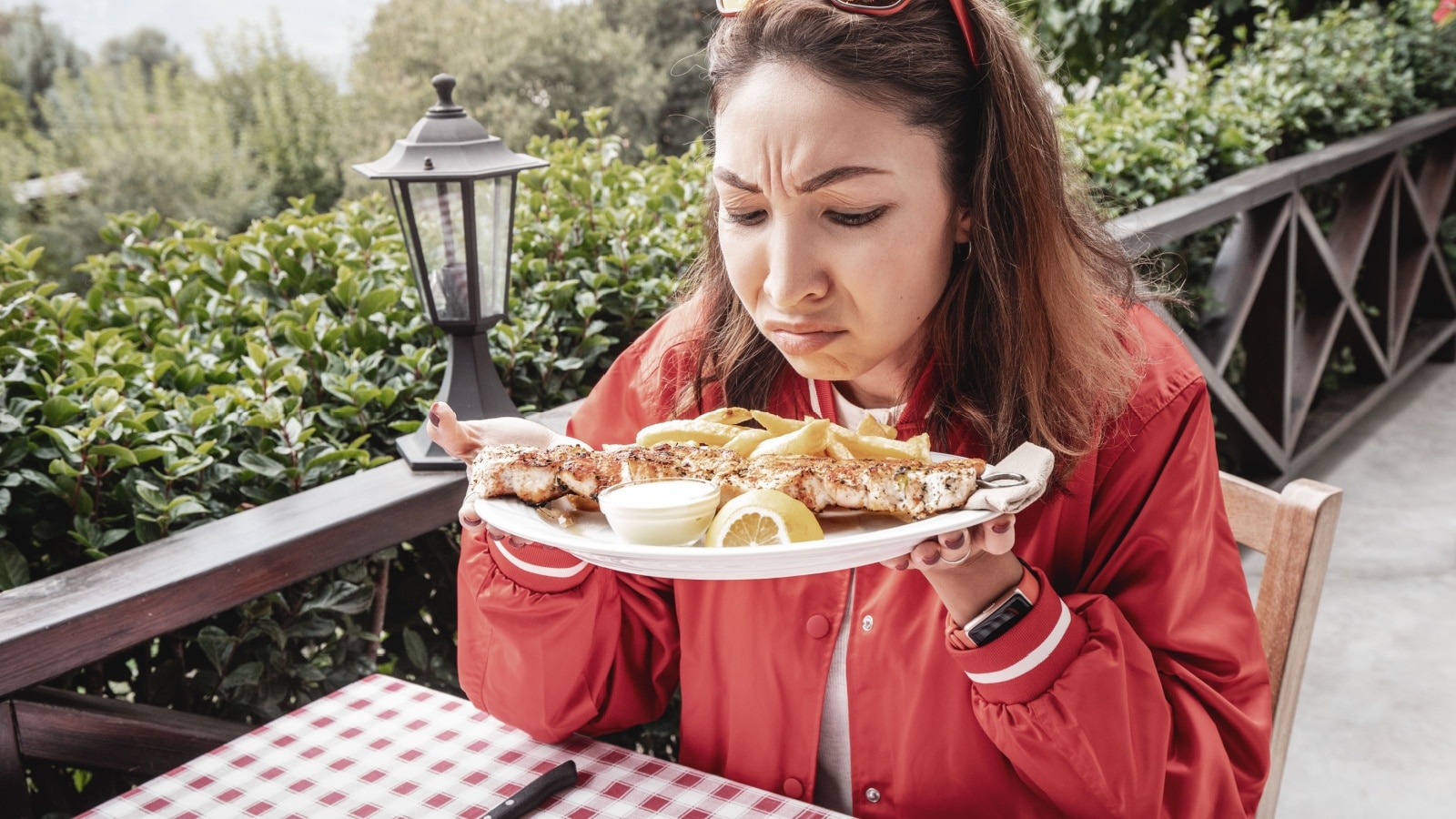 A woman dining out sniffs her food suspiciously to represent restaurant red flags.
