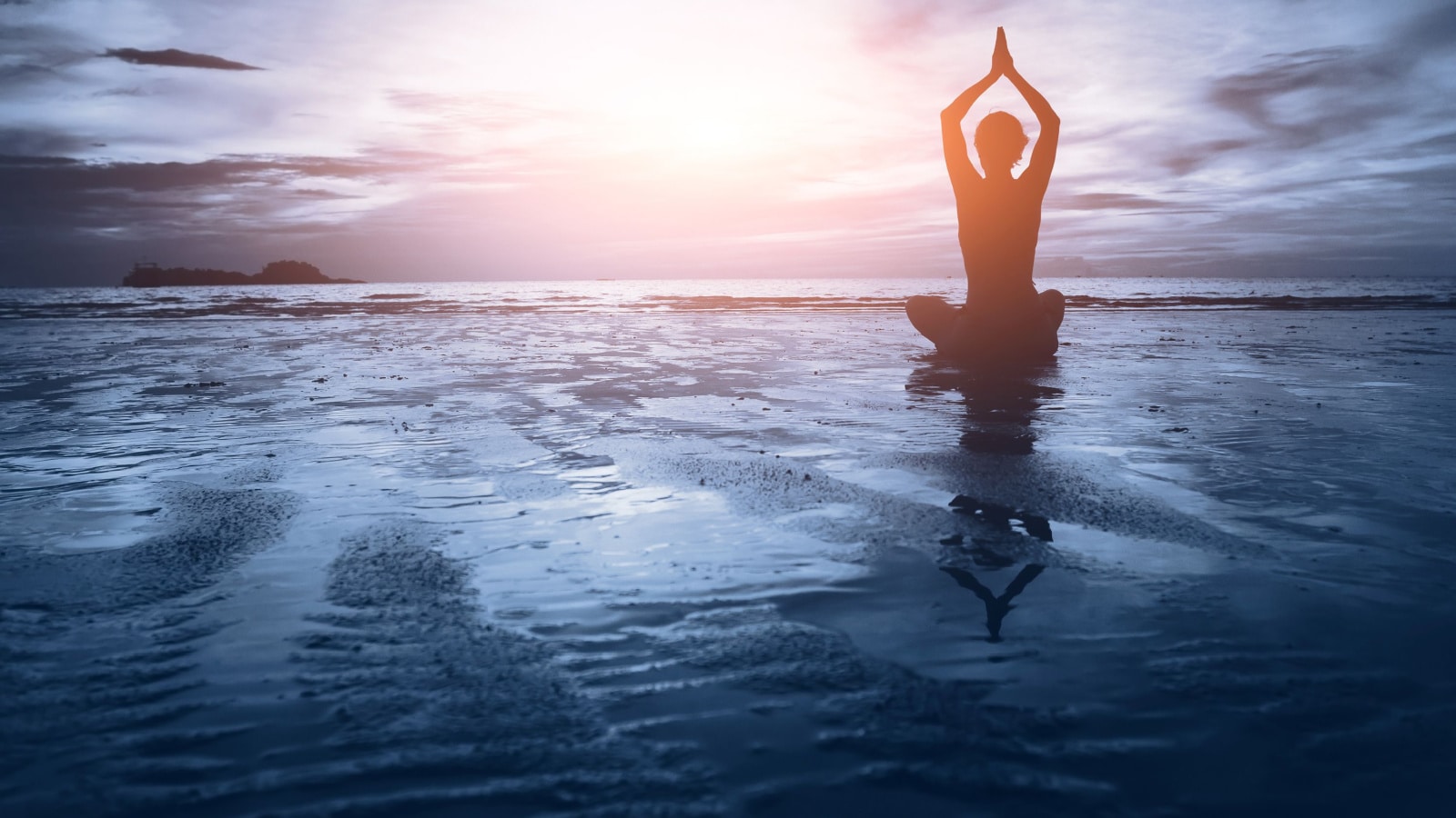 Wellbeing concept art. Person meditating with their hands over their heads on the ocean surface near dusk.
