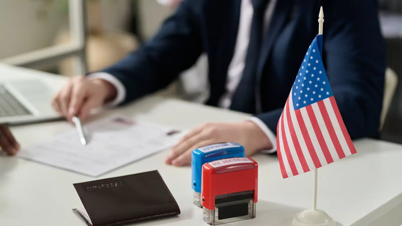 Mock up of a worker at a US embassy helping someone with documents.