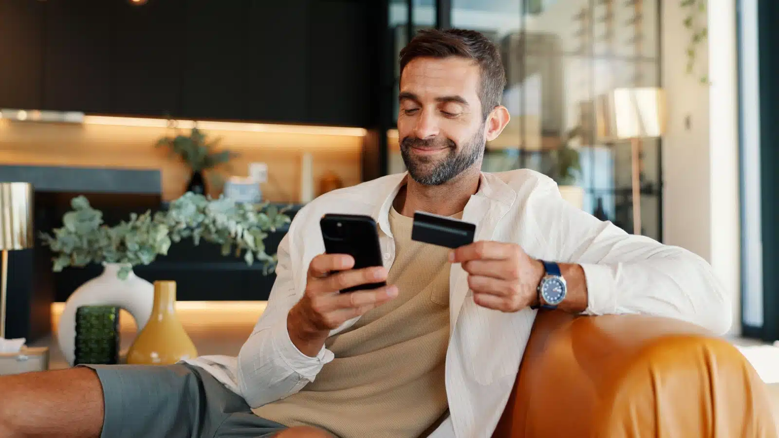 A happy man uses his credit card for online shopping. 