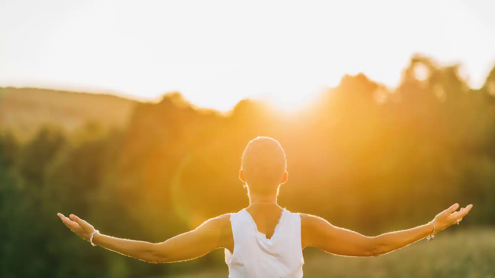 A woman with her arms open in the sunlight to represent acceptance.