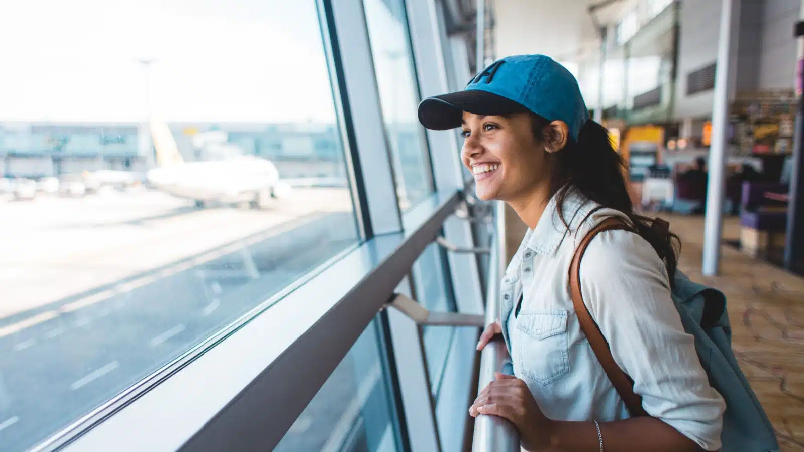 An excited woman waits for her flight at the airport.