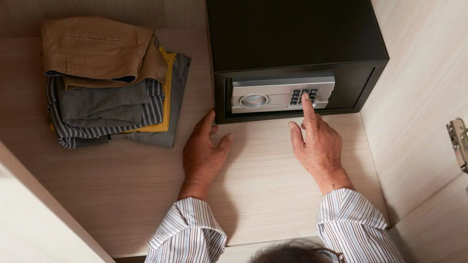A man using the safe in his hotel room.