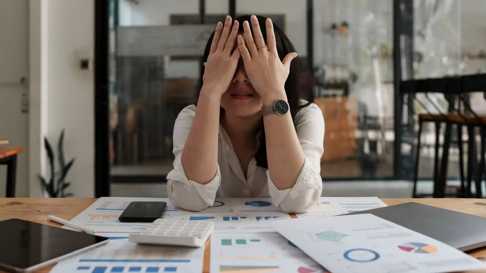 An overwhelmed woman surrounded by financial statements. 