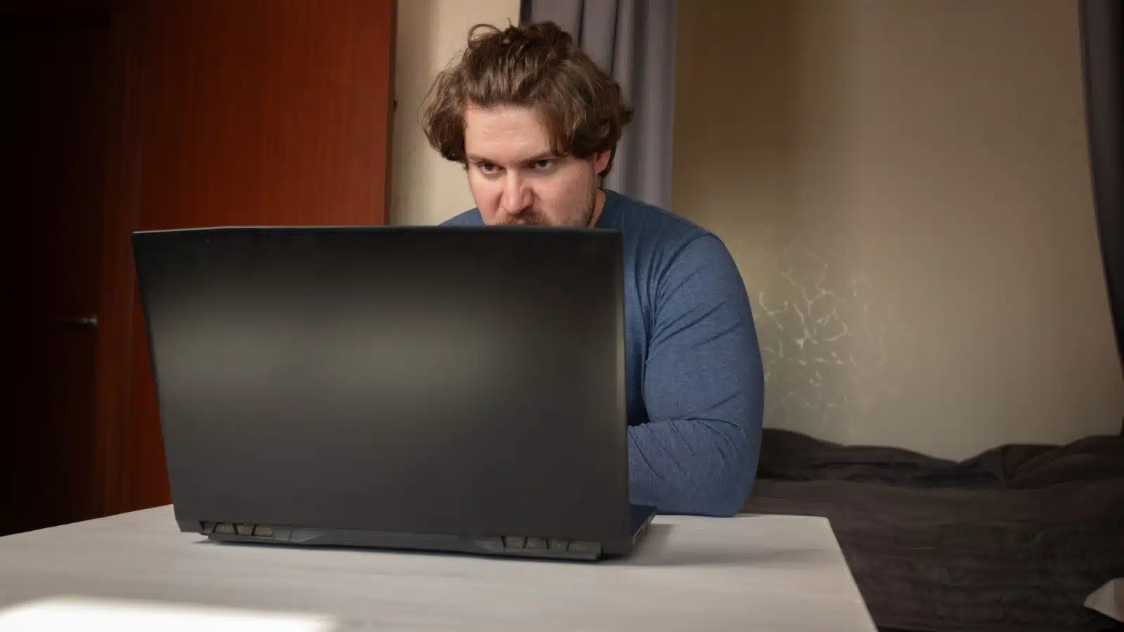 A man angrily typing behind his laptop to represent a Reddit Mod, one of the most hated hobbies. 
