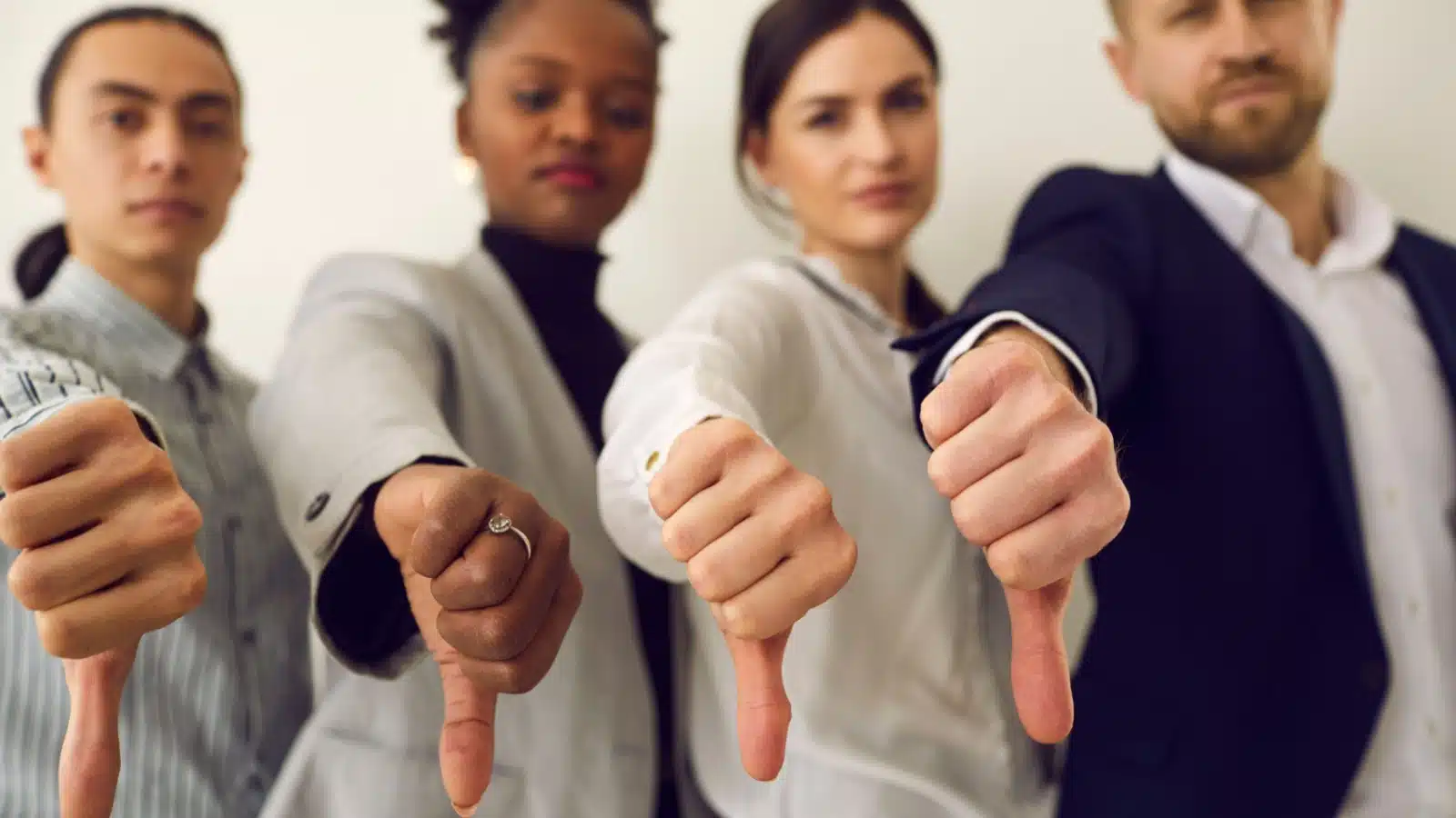 A line of professional young adults with their thumbs down to represent a bad idea.